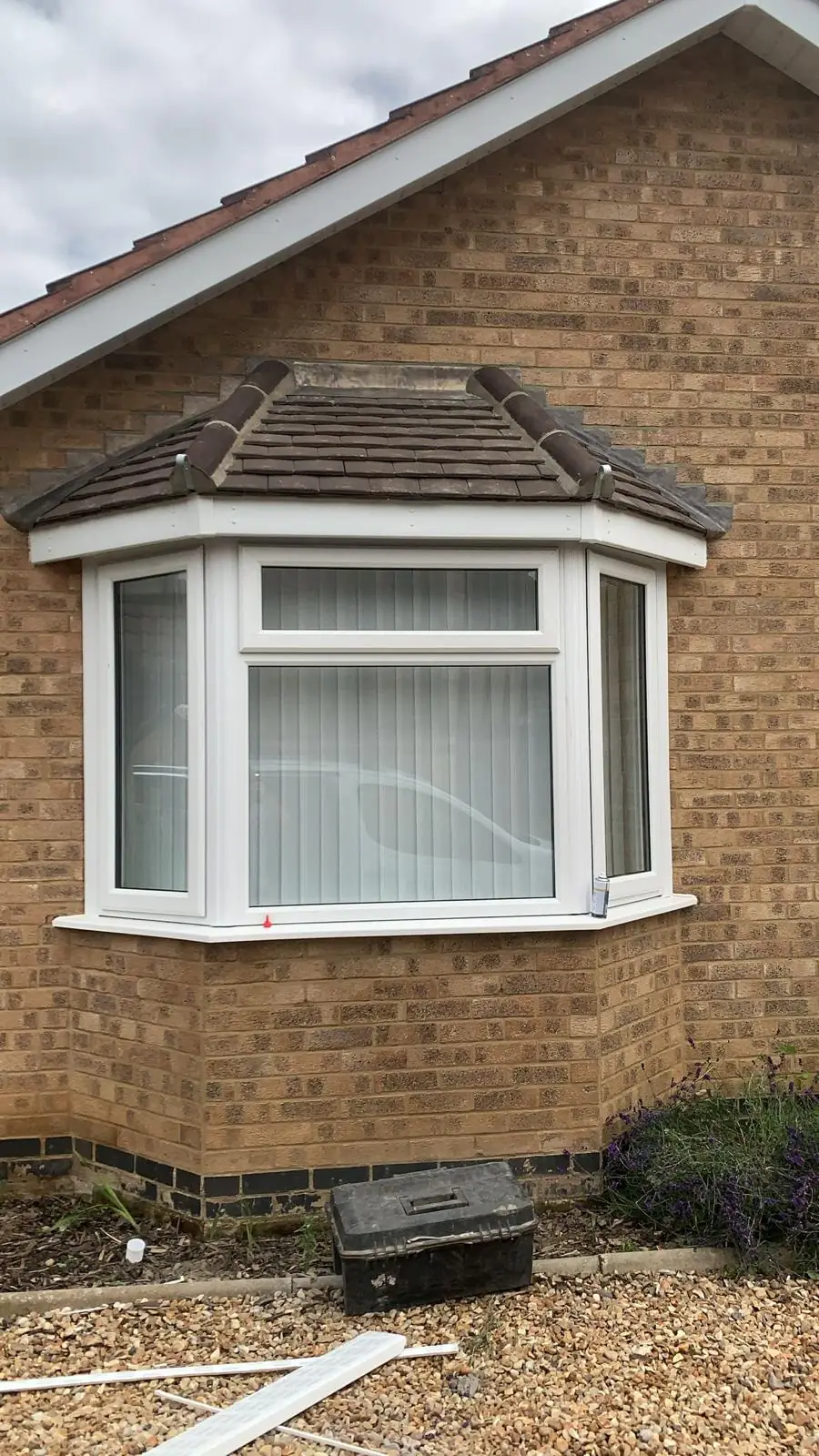 A finished bay window canopy tiled in grey on a yellow brick house