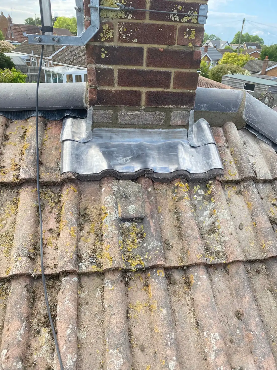 New lead flashing dressed around a brick chimney stack on a clay pantile roof