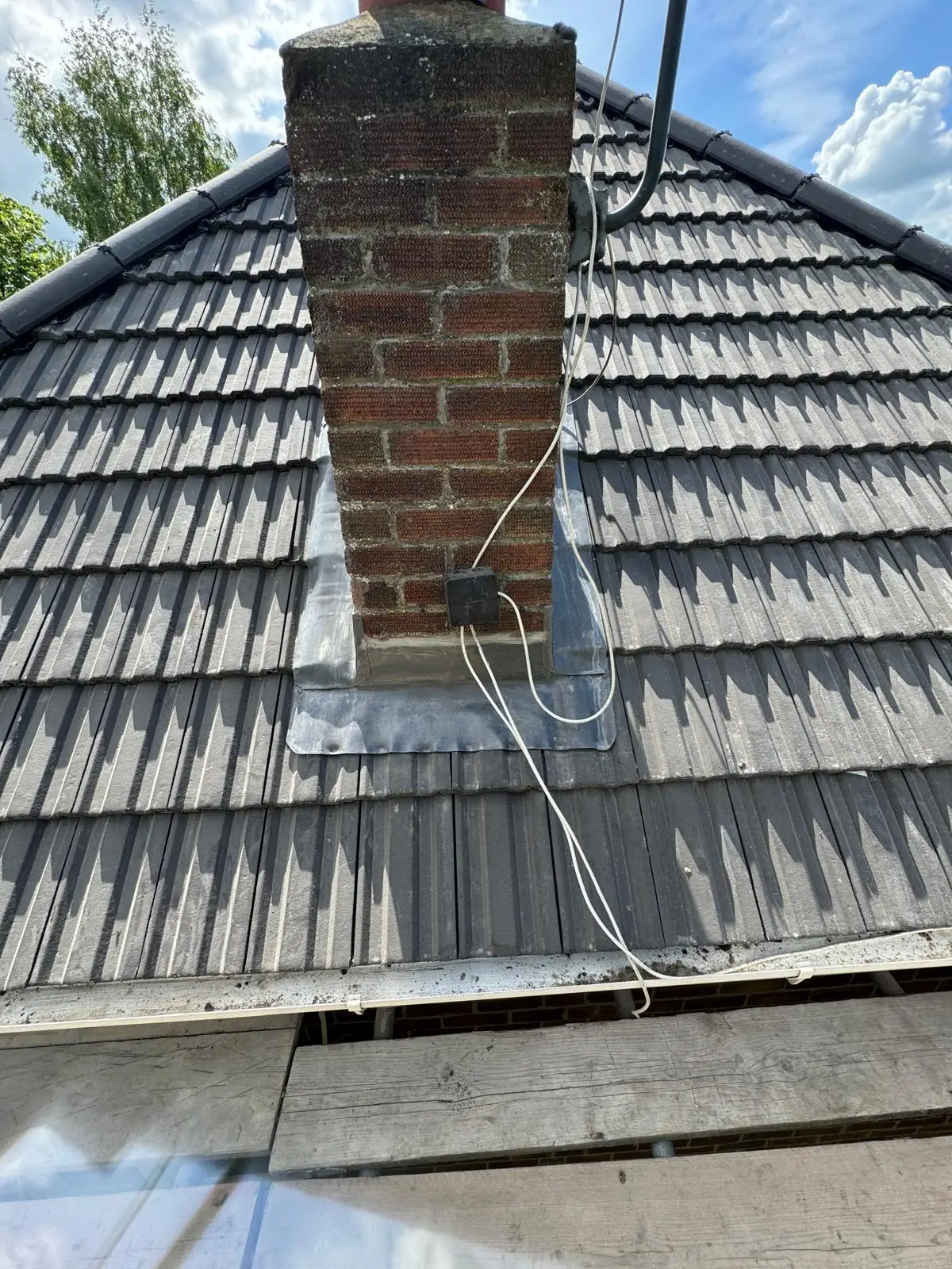 A chimney stack with fresh lead flashing set into a dark tiled roof