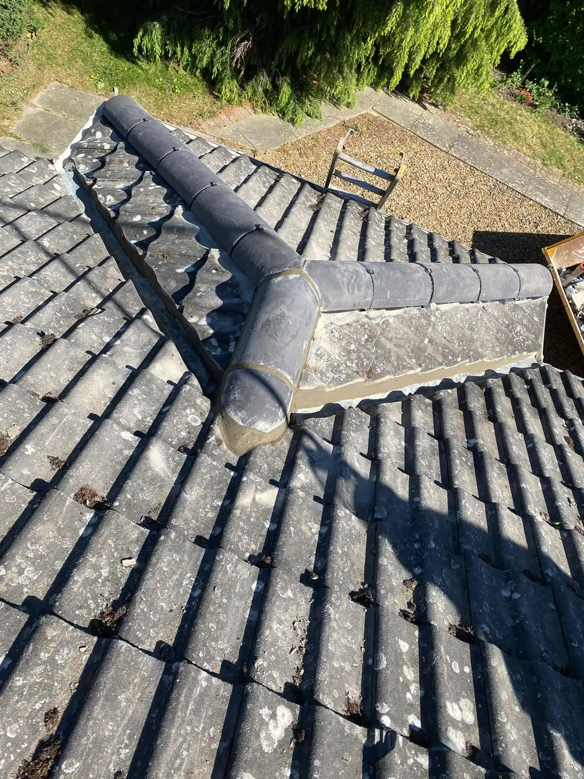 A grey flat roof section meeting an existing tiled roof