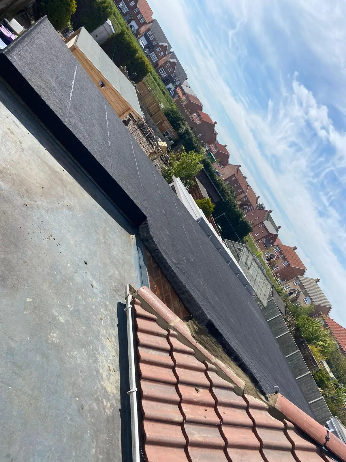 A newly laid flat roof with rooftops visible beyond