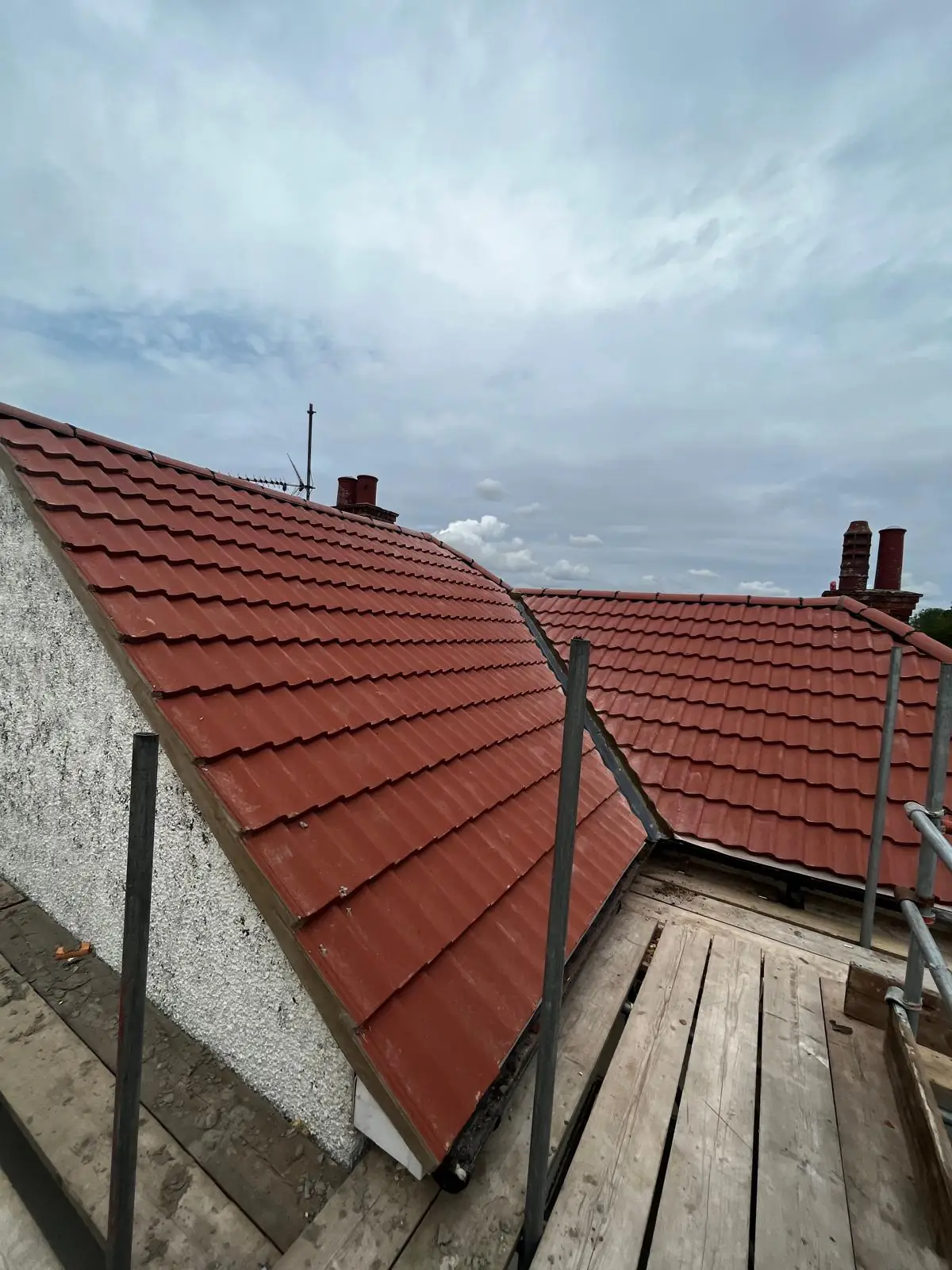 A newly finished red tiled roof with the scaffold boards still in place