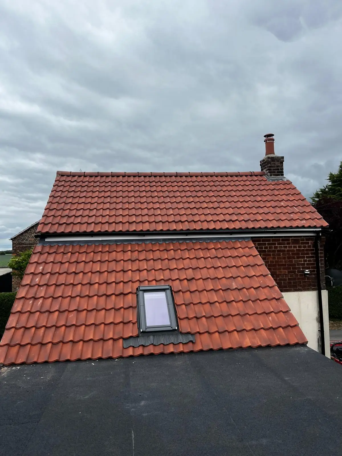 A finished red pantile roof with a rooflight fitted into the slope