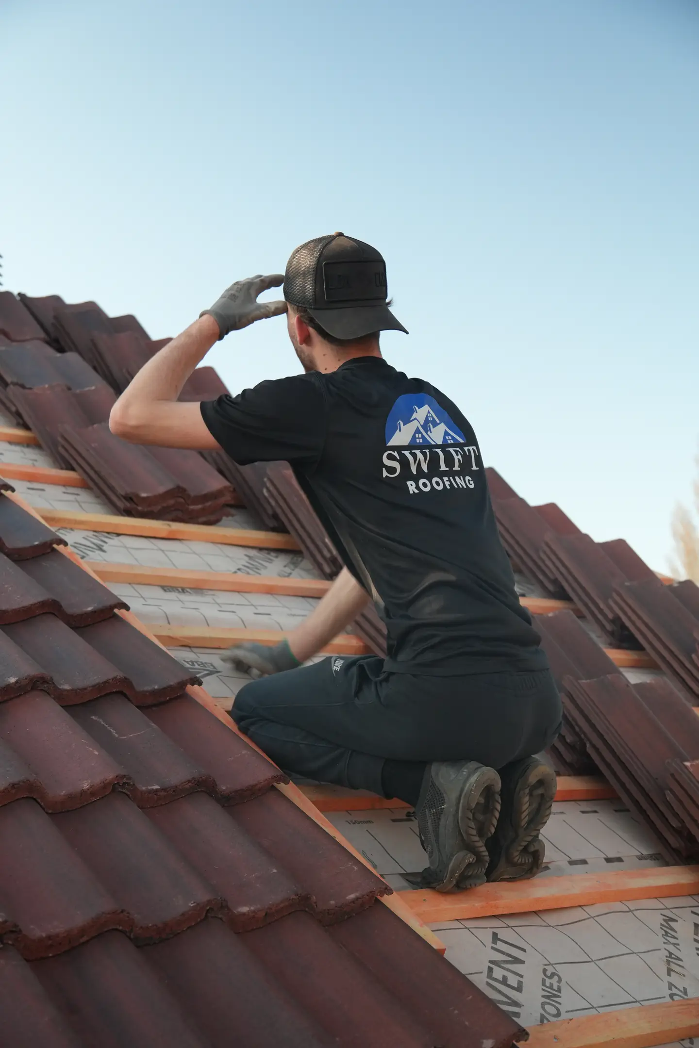 A Swift Roofing roofer in a branded t-shirt working along the batten line