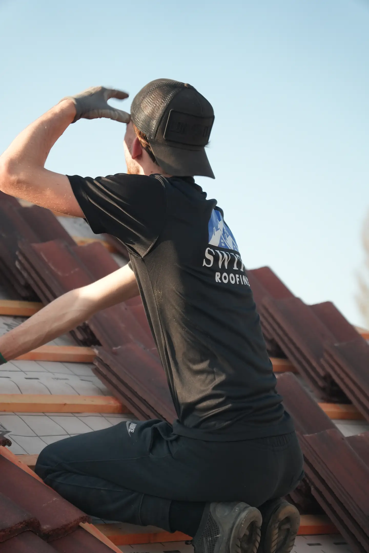 A Swift Roofing roofer lifting a concrete tile into place on new battens
