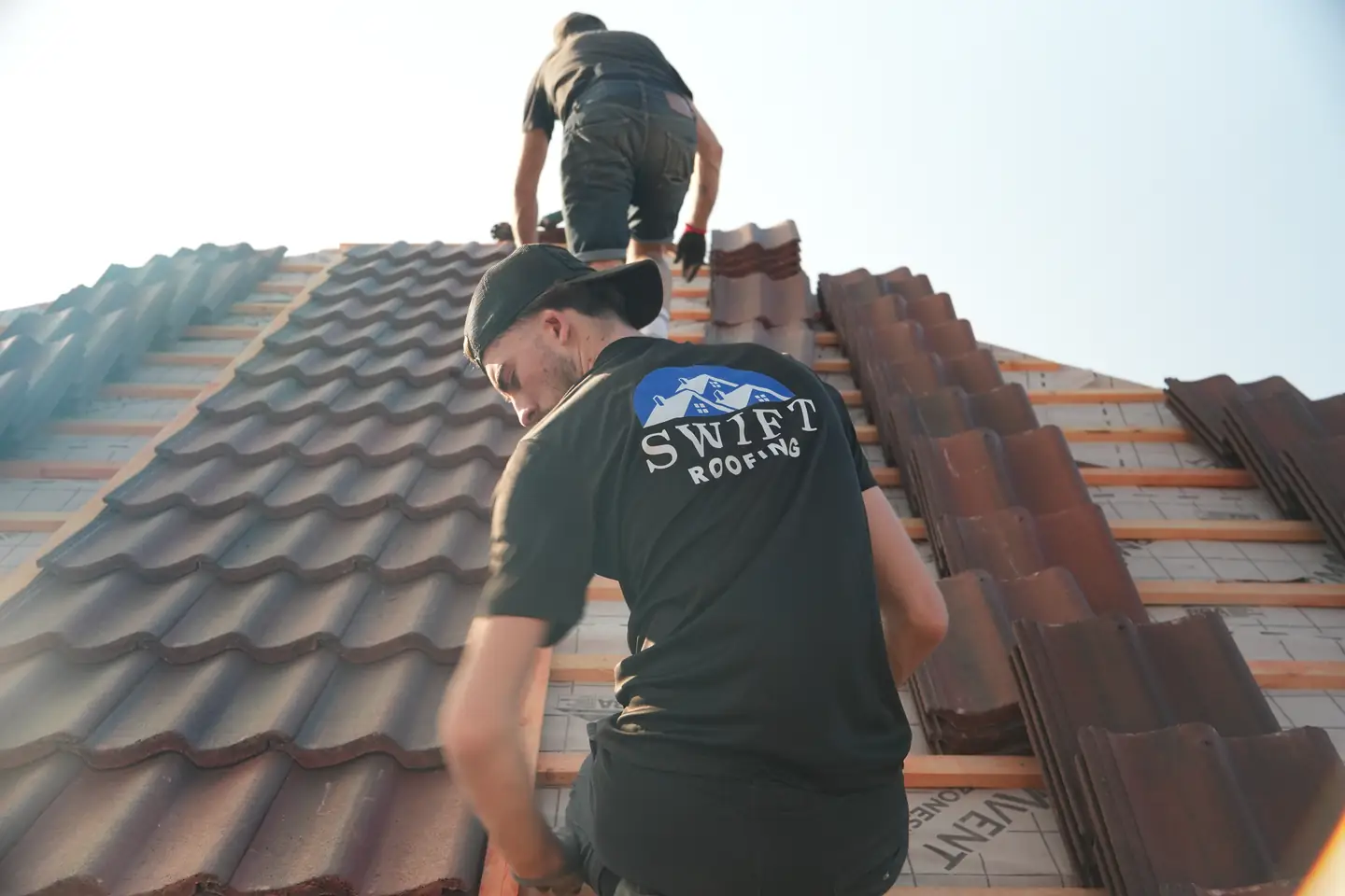 A Swift Roofing roofer tiling towards the ridge on a re-roof