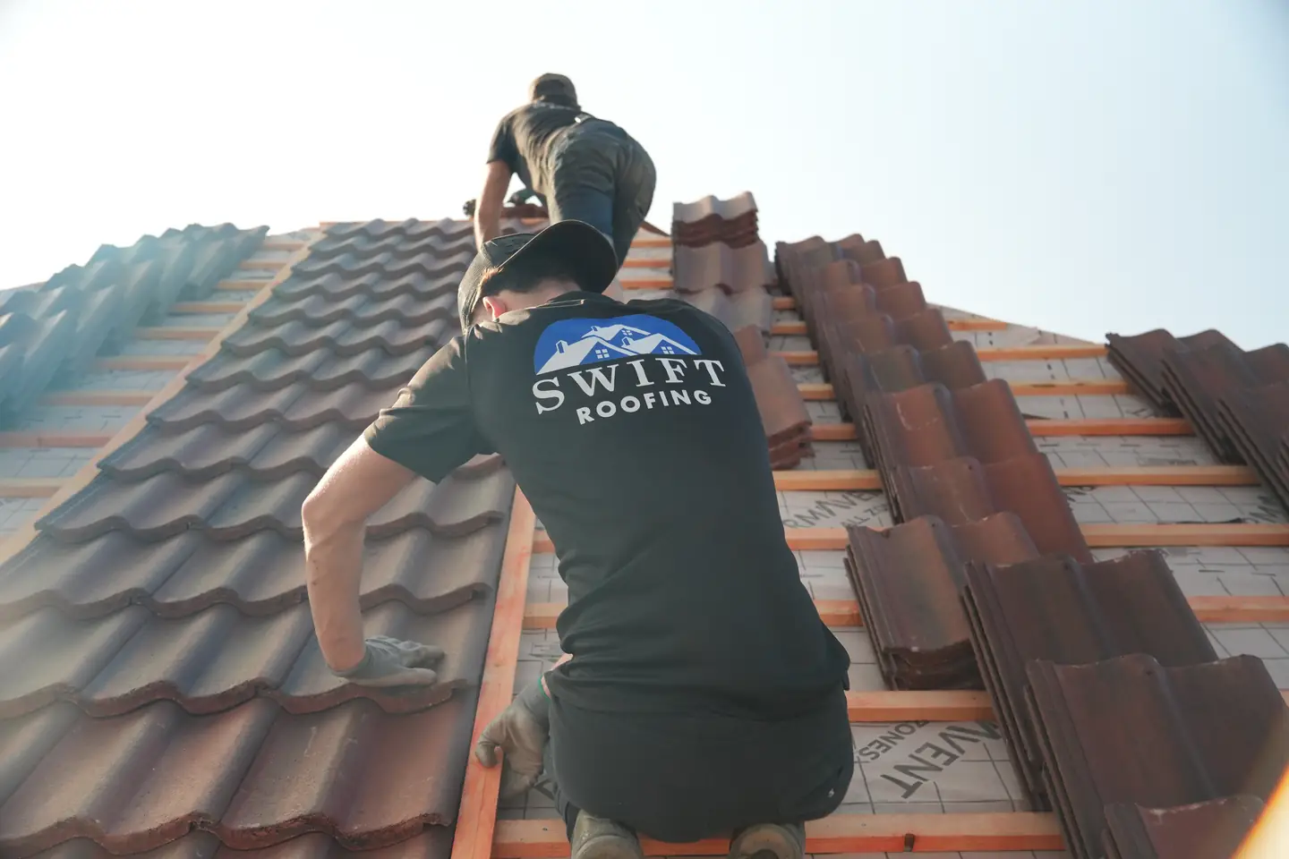 The Swift Roofing team working across a half-tiled roof