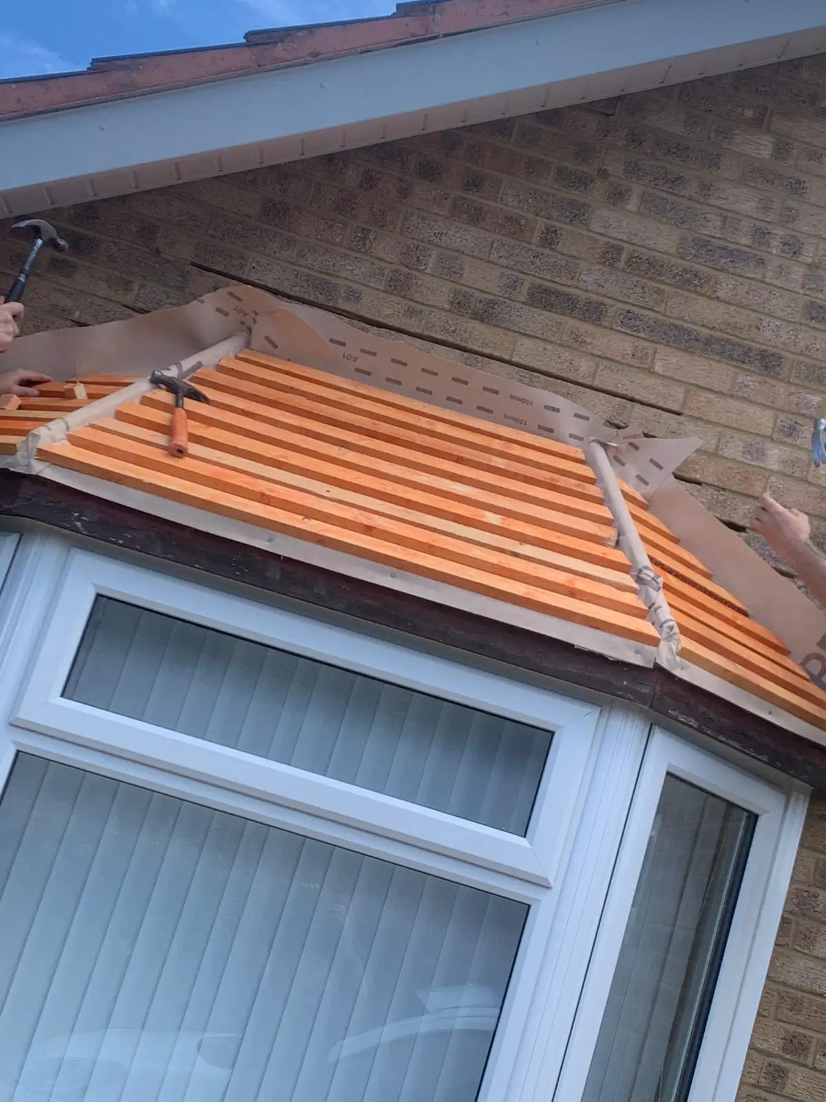 A bay window canopy re-tiled in terracotta above a white bay window
