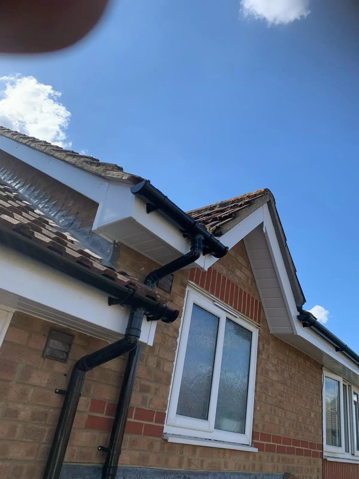 New black guttering and white fascia fitted to a red brick bungalow