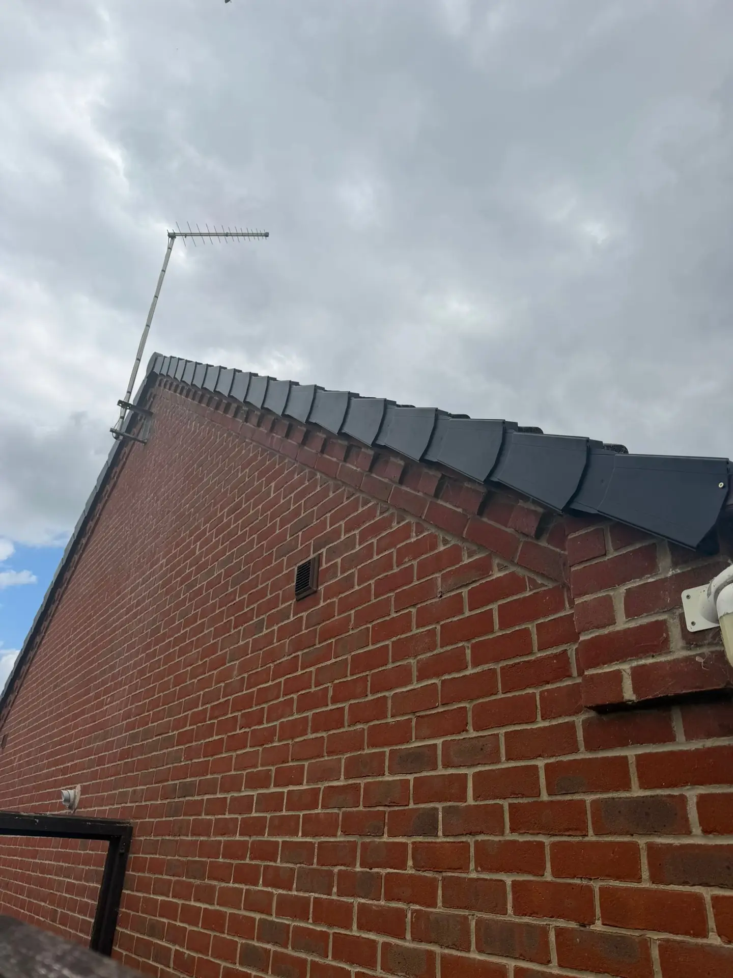A ladder set against a red brick gable during roofline replacement