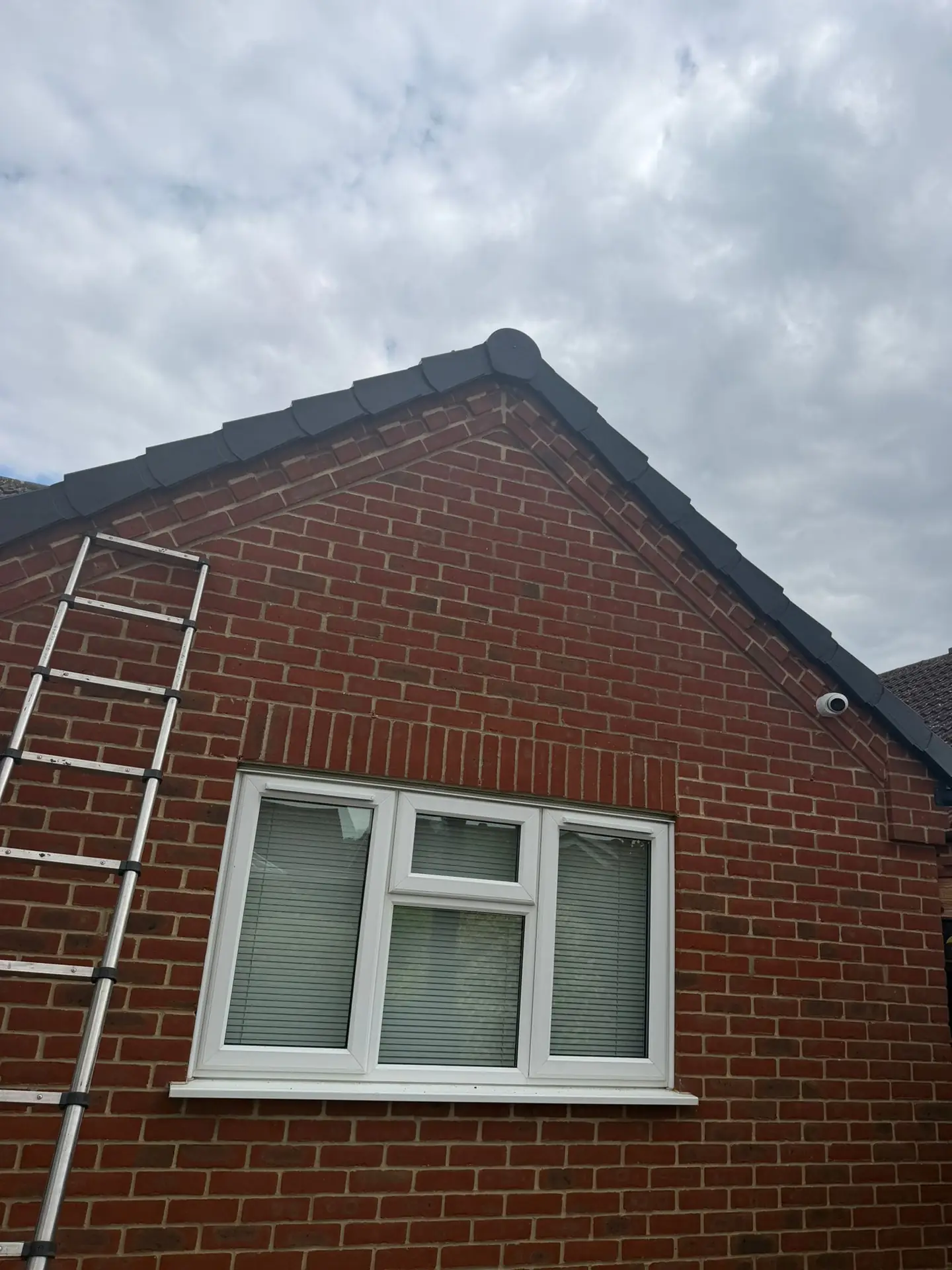 A red brick gable with the tiled roof edge and new verge completed