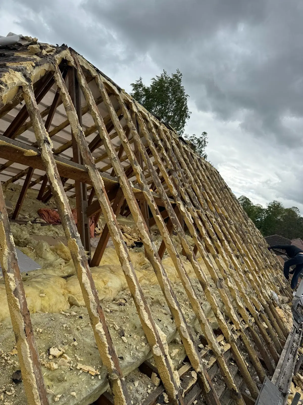 Rafters fully exposed with spray foam still between them, part way through a strip out