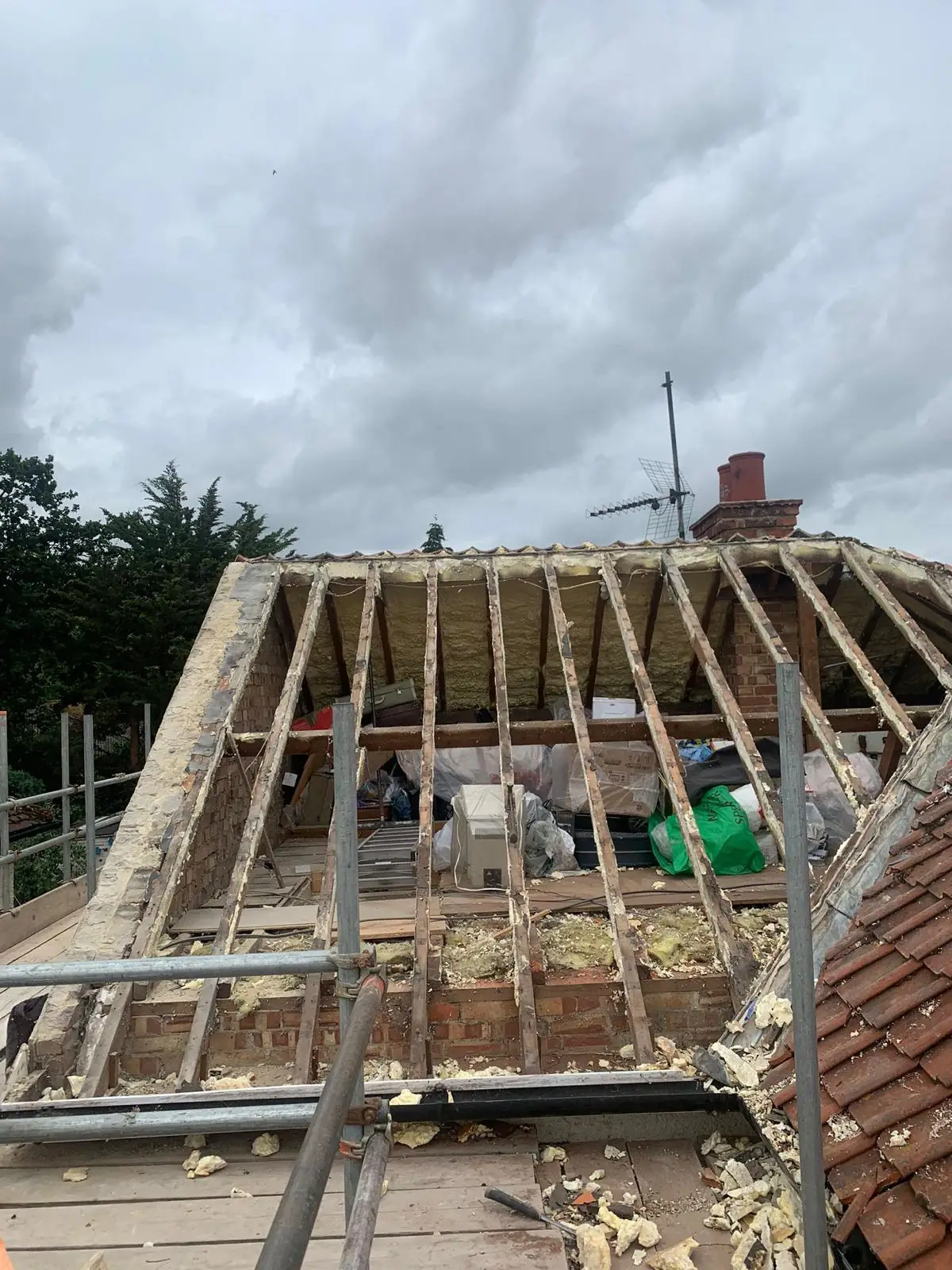A roof stripped back to the rafters after spray foam insulated tiles were removed, scaffold in place