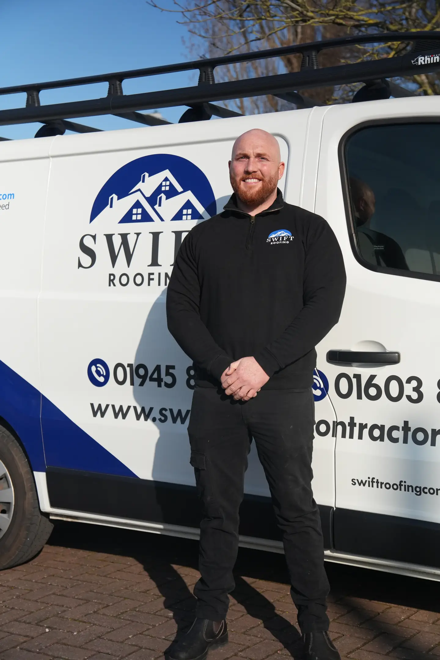 Luke Crosby, owner of Swift Roofing, standing beside the branded company van
