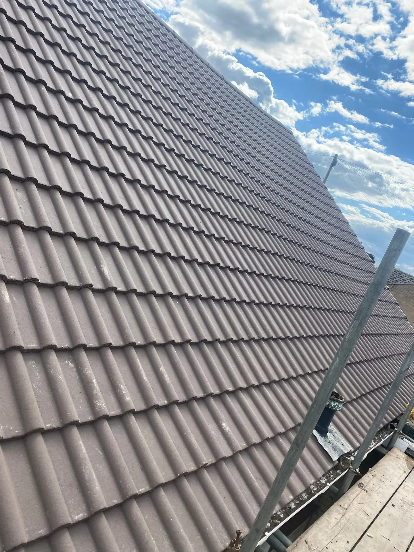 A completed brown concrete tiled roof under blue sky