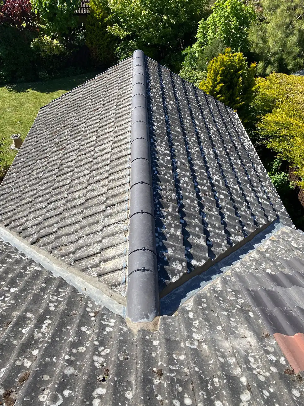 A completed grey tiled hip roof with new hip and ridge tiles bedded in