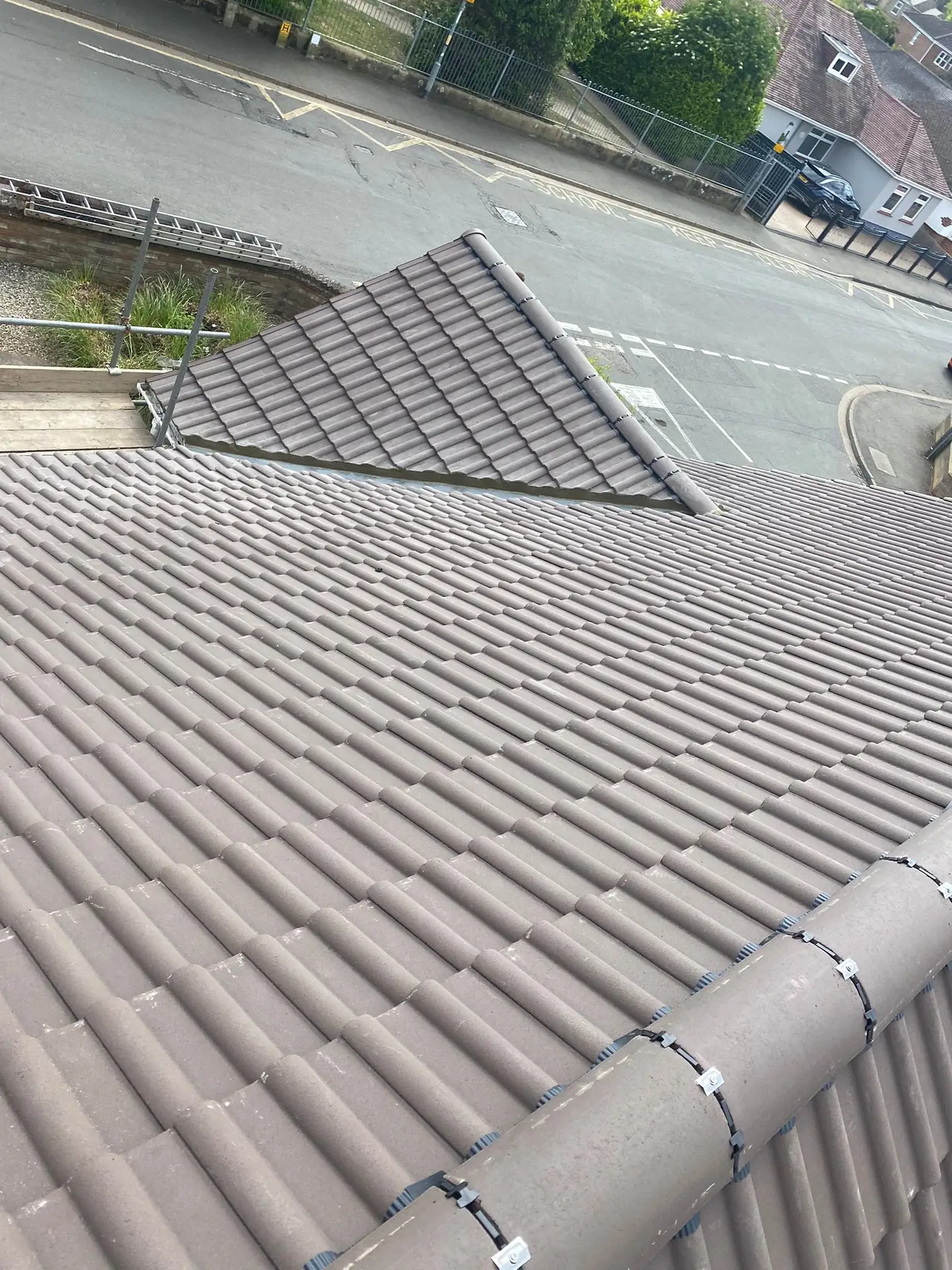 A finished grey tiled hip roof with the street visible below